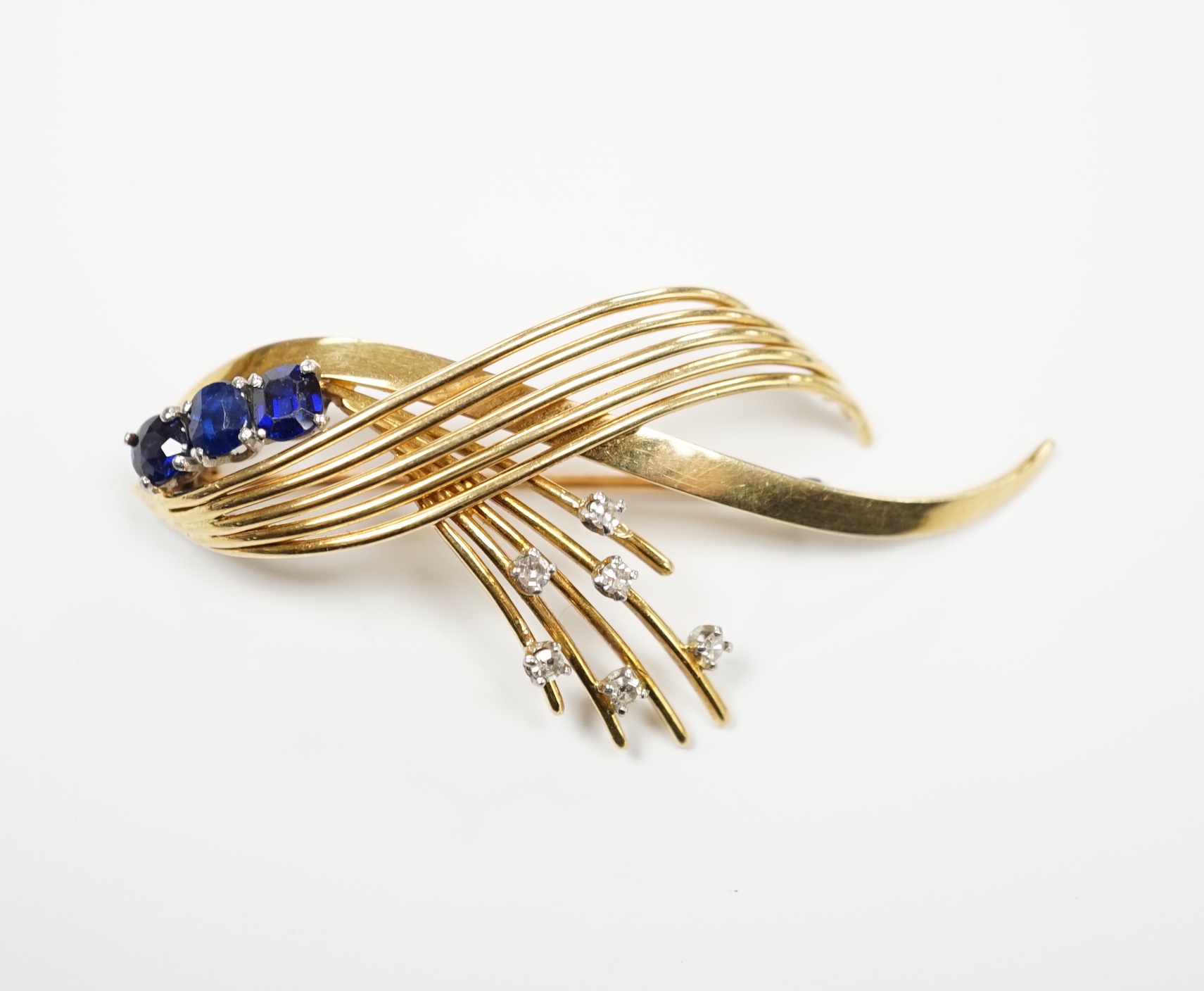 A yellow metal, sapphire and diamond cluster set stylised spray brooch, 52mm, gross weight 9.7 grams.
